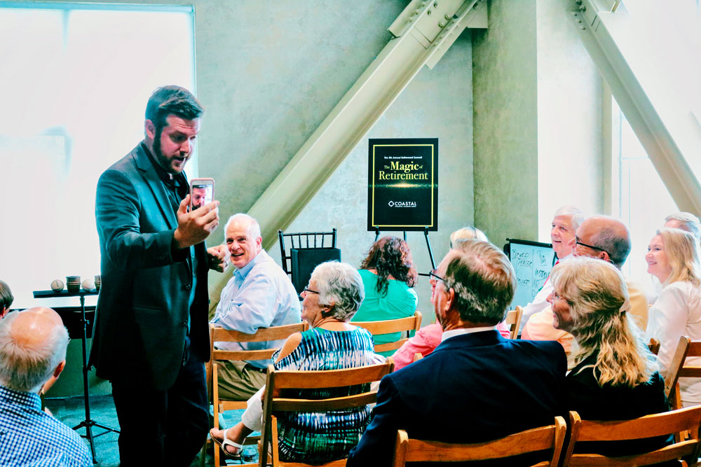 Entertaining retirees with a volunteer’s phone at Charleston, SC magic show. Magician entertaining retirees with a volunteer's phone in Charleston SC magic show